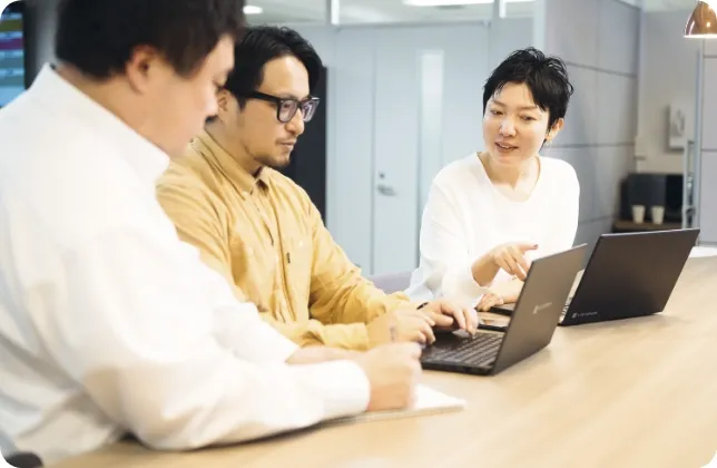 3人が横に並び椅子に座ってパソコンを見ながら話している様子