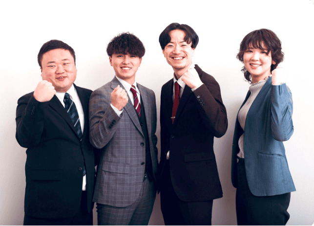 スーツ姿の4人が笑顔でガッツポーズをしているイメージ